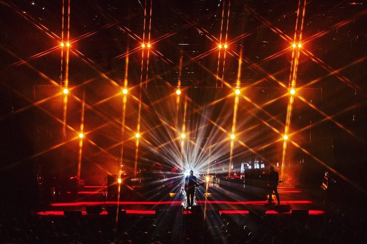 A performer silhouetted against dramatic live stage lighting